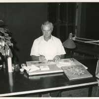 An unknown man at a desk working on artwork