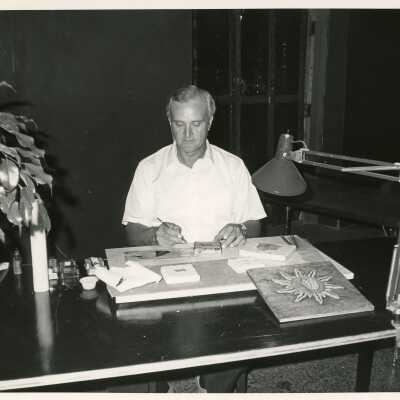 An unknown man at a desk working on artwork