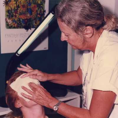 Unknown woman putting a face mask on an unknown woman.