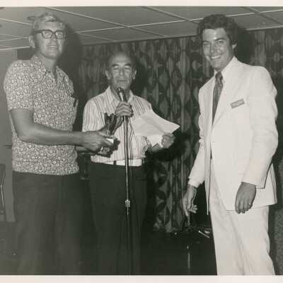 3 Unknown men standing at a microphone