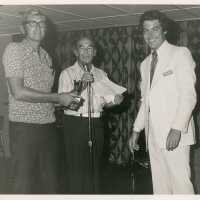 3 Unknown men standing at a microphone