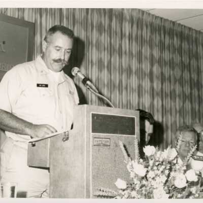 A man in uniform speaking at the podium