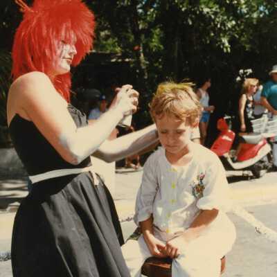 Unknown woman dressed up painting a child's hair.