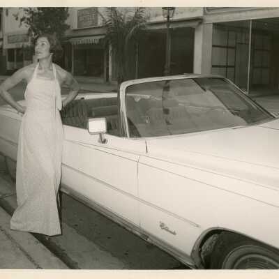 Unknown woman standing next to a white car on Duval Street