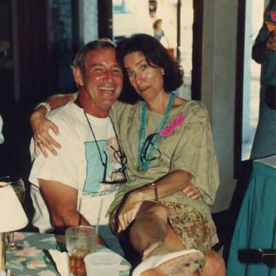 Rita Troxel sitting on an unknown man's lap at the Fantasy Fest sponsor appreciation party.