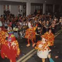 A group of unknown people dressed up walking in the street.