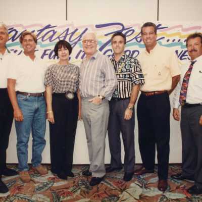 Unknown people standing in front of a Fantasy Fest sign.