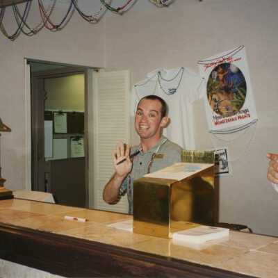An unknown man standing behind a desk.