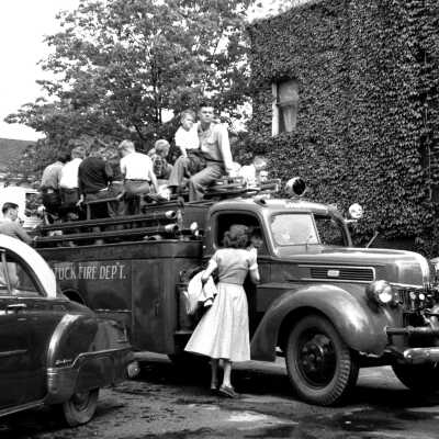 678 0/16	Saugatuck - Parade	1954	Memorial Day parade: Ev Bekken on roof of antique fire stuck next to ivy-covered drug store walls