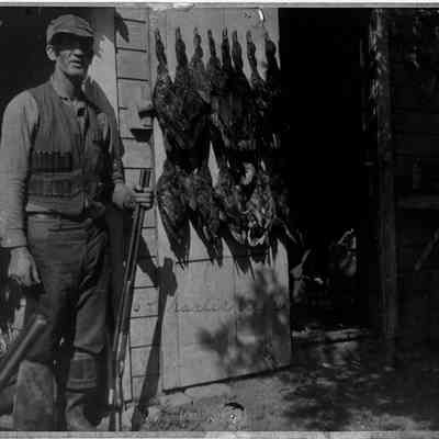 89-1-7_Chas._Ash.jpg 1MB: Charles Ash, holding a shotgun, poses with hunted ducks.