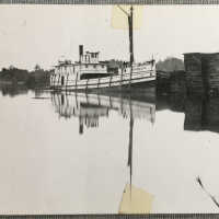 Steamer Douglas docked by stacks of lumber