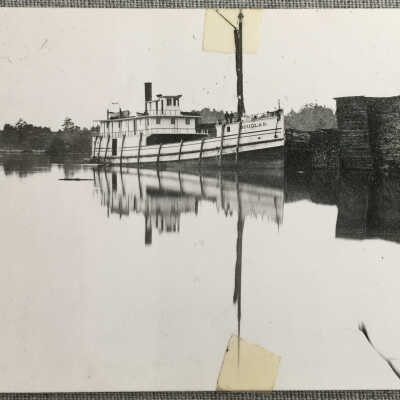 Steamer Douglas docked by stacks of lumber