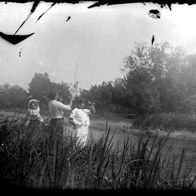drinking beer.jpg 429KB: Three people drinking from bottles near river. The man is holding a fishing pole
