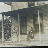          Two people (unknown) on cottage porch.; Postcard
   