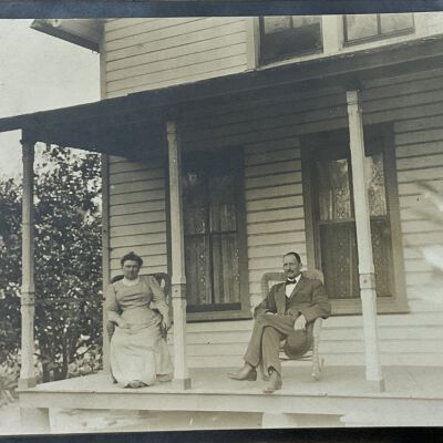 Two people (unknown) on cottage porch.: Postcard