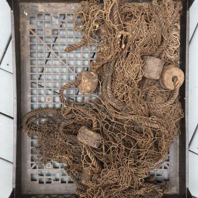 Pound (or Pond) net after boiling. Cotton net with wooden floats. This type of net was not meant to be invisible, like a gill net. Its purpose was to drive fish into an ever-decreasing funnel of netting in order to trap them.: Net installed on Shanty facade May 2021