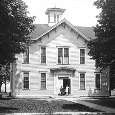 LO30 Old School ca 1910: Above - Old School House, 130 Center Street, Douglas. Standing on top of the tallest dune in Douglas and overlooking the Kalamazoo River, built by local ships carpenters to a plan provided by the State of Michigan. This school was revolutionary in its day because it was a multi-classroom/multi-teacher school and because it was of such grand architecture for the village—which in 1866 had very few buildings of architectural note.