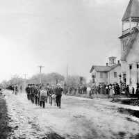         LO Ganges parade 1907; The parade to the cemetery forms about 1907 in front of the Ganges ME Church. In the background is the old Ganges Union School which was razed in the 1950s and replaced with a one-story brick building. The white clapboard Methodist Church burned in 1929 and was also replaced in brick.
   
