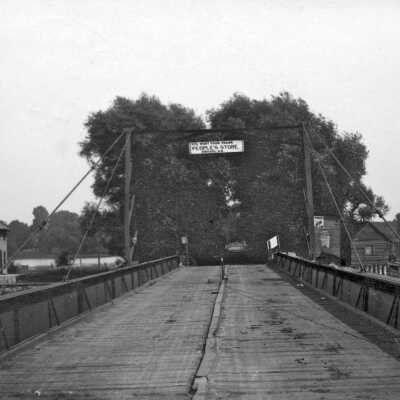 Caption for this photo when it was reprinted in the 20 Aug 1970 Commercial Record: The old swing bridge between Saugatuck and Douglas. Building to the left is the bridge-tender's house. Those on the right were located on an island (now site of Pier Marina) between bridges and housed mostly Indians who worked in the Douglas basket factory. Photo courtesy of Mr. and Mrs. G. Edward Wark.
