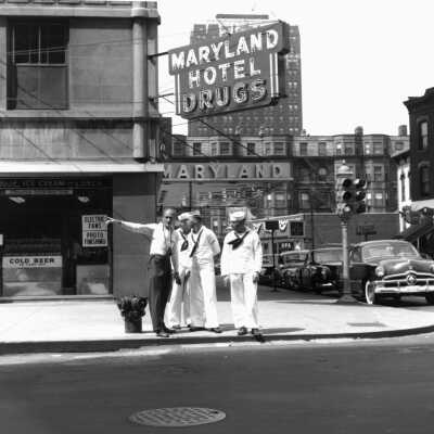 832: Maryland Hotel Drugs, Three sailors and a man in civilian clothing on a city street corner. A print of this photo is in box 209 Bill Simmons.