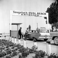          638 0/4 bw	Saugatuck - Beach	1957	Oval entrance, parking 25 cents a638.jpg 2.1MB; At the Oval Gate
[The picture on exhibit poster and the cover of the book] The girls are identified as Susan (Floto) Sisson driving the car she received as a graduation present with Bonnie (Sewers) Kozanecki beside her. In the back seat is Diana (Meyer) Kausen). - Bonnie Kozanecki
A Blue Ford
The car in #638 is my 