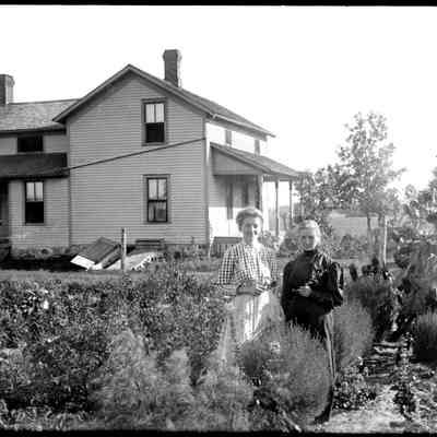 Sim Garden scene 600KB: Two women stand in a garden by a farmhouse.