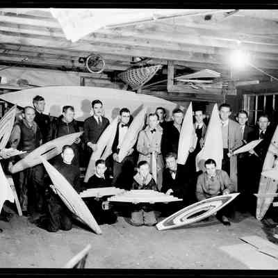sim model yacht club sk159.jpg 810KB: Men and boys holding up their model sailboat hulls in a workshop. Pond boats. Location may be Carl Bird's boat workshop
