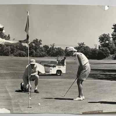 Potter Curran, unknown kneeling man, Susan Switzer Fons, Jerome Switzer: Westshore Golf Course St. Louis at Douglas golf joust. Woman putts while three man watch. Photo by Don Heuchan of St. Louis, MODate stamped July 23, 1965.