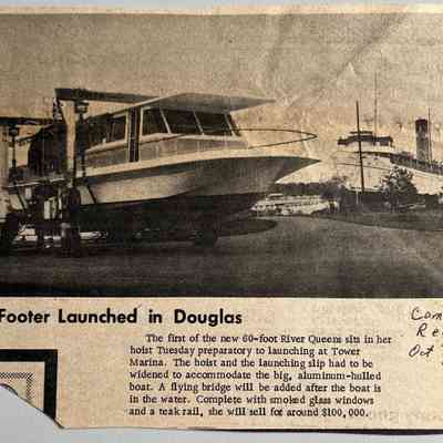 60-Footer Launched in Douglas: The first of the new 60-foot River Queens sits in her
hoist Tuesday preparatory to launching at Tower Marina. The hoist and the launching slip had to be widened to accommodate the big, aluminum-hulled boat. A flying bridge will be added after the boat is in the water. Complete with smoked glass windows and a teak rail, she will sell for around $100, 000.