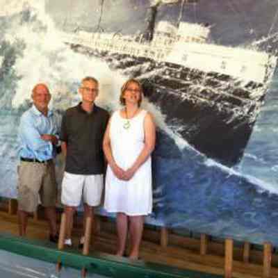 Randall Higdon, Chicora artist visits Shipwreck Exhibit Site: Randall Higdon, artist of the original image of the Chicora 'lost at sea' visited the Boathouse exhibition barn at the History Center on July 2. He is pictured above with Kristi Mueller, the volunteer graphic designer who converted the original 22"x48" painting into a 47ft x 9.5ft mural for the boathouse exhibition "Rowing them Safely Home," along with Jim Schmiechen, exhibition curator-writer.

Randall Higdon is a well recognized Michigan artist with a studio in Coloma, MI. The original painting was commissioned by the Society in 2002 and is now in the possession of Andrew Plummer of Douglas. The enlarged digitized image, with names of 100 shipwrecks, was then produced by Agio Printing in Kalamazoo under the direction of John Capotosto.

https://sdhistoricalsociety.org/Newsletter/2012/jul12/jul12_newsletter.htm