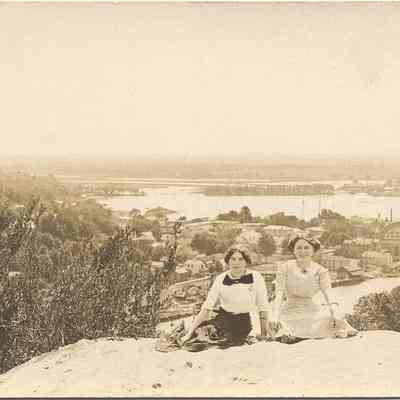 022.TwoGirlsonBaldhead.Super!!!!.jpg 140KB: Two woman kneel in the sand atop Mount Baldhead with the Big Pavilion in the background. Two ladies sit. Two girls.