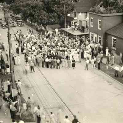 CWPC-0484FennvilleHardware.JPG 212KB: People gathered to listen to a band set up on the roof of  a porch. Sign for Fennville Hardware on building next door
