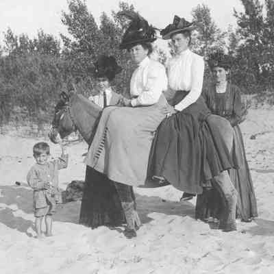 WomenOnDynamite.jpg 515KB: Four women, two on Dynamite, two standing behind with a boy holding the Donkey's lead