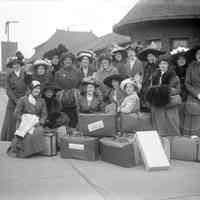          KColGaynorOrig.jpg 2.3MB; The Gaynor Club
These are the members of the then well-known K College women’s glee club. Extravagantly hatted and furred, they await a train that will carry them off for a weekend singing date. In the back row, the woman fourth from the left is faculty. Also in back, Florence Hartman with her ever-present pince-nez is just to the right of the girl with bird wings on her hat. The cop seems to be sans pistol but has a big stick and is keeping a sharp eye on things. Perhaps there was an ordinance against giggling. Even that seems unlikely with this well-behaved bunch.
George took this with his 5x7 view camera. He probably had to carry the big
camera case and tripod the half mile down hill from the college to the station. I wonder, did the girls help? From the direction of the eyes of some of his subjects, I’d guess he stood to the left of the camera with his rubber bulb and said or did something silly to get them all to smile. In the exact center of the back row stands a pretty girl with good cheekbones. Did she choose that spot — or did George?
Surprisingly, the Kalamazoo train station has hardly changed at all in the
ninety years that have passed.
   