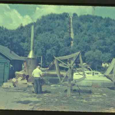 SewersFishhouse.jpg 1.4MB: Sewers fishing operation on Water Street with green shanty, fish boxes, boiler for steaming/disinfecting nets, two men winding cleaned nets on reels. Mt. Baldhead in the background.