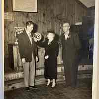          Memorial Day 1954; Lillian Morris pins poppy on lapel of Mr. Sholders[?] the president to Douglas village with Mr. George Wright, president to Saugatuck Village. Location: American Legion post 137 hall.
   