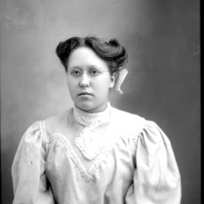 Woman_in_blouse.jpg 333KB: young woman with round glasses are hair tied up with a bow