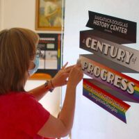          Sally Winthers installing the door graphics at the Saugatuck-Douglas History Center, September 2021.; Main floor, east gallery
   