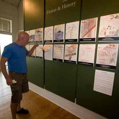 James Schmiechen, museum chair, checks out a student's short story, displayed underneath the drawings.
