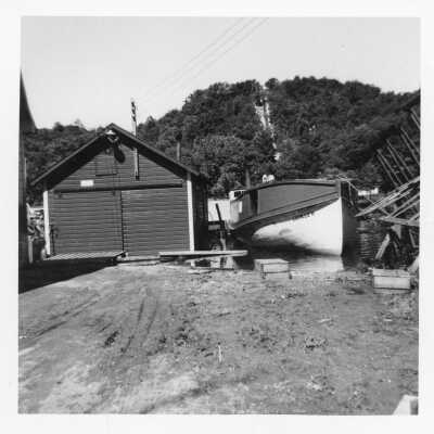 The Lucille H, a 48-foot tug owned by Ralph Cross was on eof the first wood-hulled tugs to be encased in steel. Moored at the Sewers docks off Water Street. Mt. Baldhead stairs in the background.