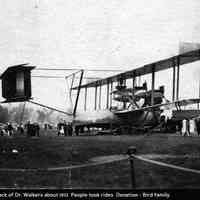          bf013.jpg 327KB; On back of photo: Field back of Dr. Walkers about 1912 People took rides Donation - Bird family -- people gathered around to view an early biplane or aeroplane or airplane
   