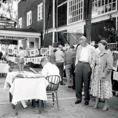 pavillionArt.jpg 421KB: Art fair with clothesline and male artist at table.