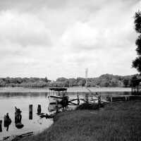          697 0/1	Saugatuck - West side ferry landing with the motorized ferry boat; 39A389 ca 1943 The Isabel at the ferry landing – foot of Butler Street
George B. Tisdale was a Great Lakes sailor. He retired from the Lakes and took over running the West Shore as a ferry between downtown Saugatuck, Douglas and the west side of Kalamazoo Lake during the last illness of the boat's owner, John Campbell. 
In 1927 Tisdale built the Isabel (named for his daughter), from a Bay City company's pre-cut kit. When the late Robert Wolbrink was a youngster he used to like to sit with Captain Tisdale on a bench at the end of the dock near the Tisdale house (now the Deer Creek Bed and Breakfast) on the southwest shore of Kalamazoo Lake. From there they could see the semaphore signals at the foot of Butler Street, and near the old swing bridge into Douglas that meant that there was a customer waiting. Wolbrink said that Tisdale once told him that he had given up sailing on the Great Lakes because it was making a drunkard of him, since whiskey was the only possible way to keep warm on a drafty lumber boat. According to Wolbrink, Tisdale also had a large red nose that made his story even more believable.
   