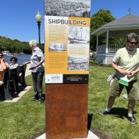          Installation of the interpertive panels on the steel makers, June 2, 2022; Julie Bizzis (gray shirt talking with people on bench) and Laura Peterson (with wisk broom)
   