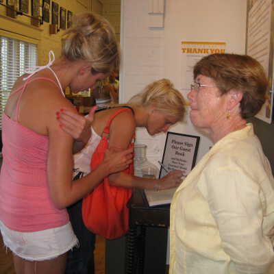 Visitors signing guest book: Cindy Osman (in yellow shirt) docent