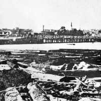          Ca 1874 photo taken from the Saugatuck side of the river. A portion of the 1870 bridge is seen in the center. The 1866 school is visible just behind the pile driver on the upper right.; filename: LO94 Douglas School
   