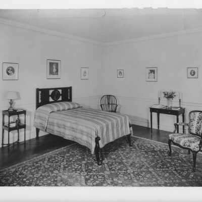 Hammond mansion bedroom with bed, chairs, and paintings