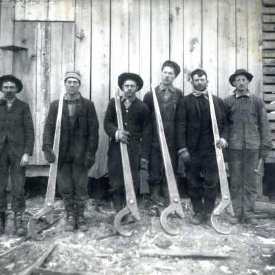 Sawmill workers holding cant hooks or Pipeliners holding lay tongs