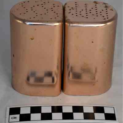 Back and size comparison of copper salt and pepper shakers.