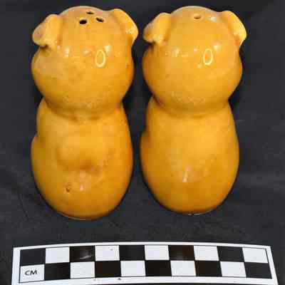 Back and size comparison of yellow pigs salt and pepper shakers.